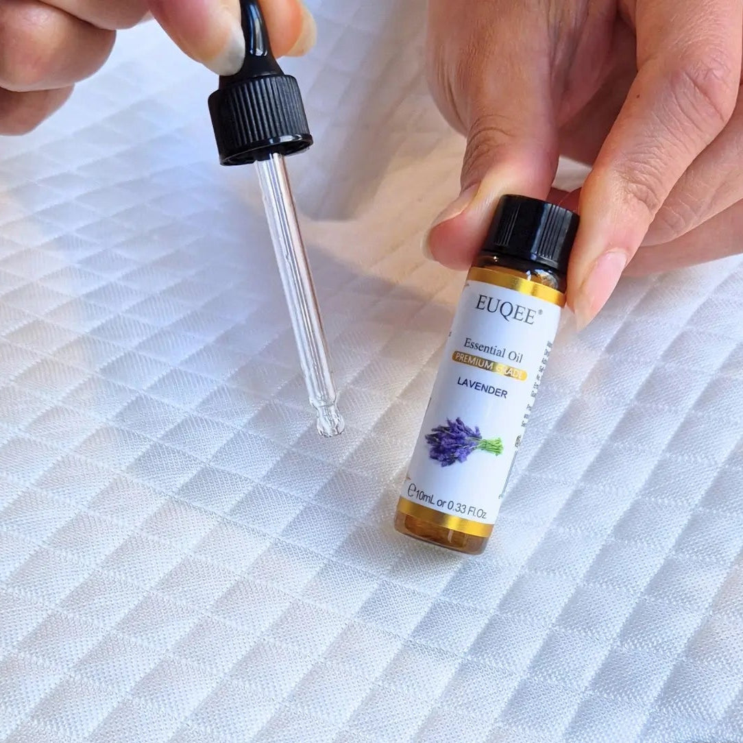 Person holding a bottle of essential oil with a dropper on a textured surface